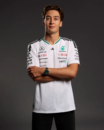 Person wearing a white sports jersey with various sponsor logos on a dark background
