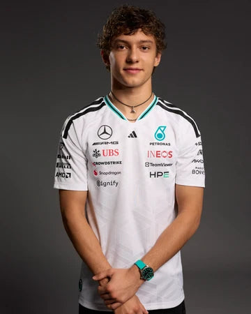 Person wearing a white sports jersey with various sponsor logos on a dark background