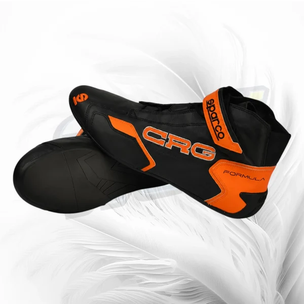 A pair of black and orange CRG Formula cycling shoes with the brand name 'Sparco' visible on the ankle strap, set against a white feather background.