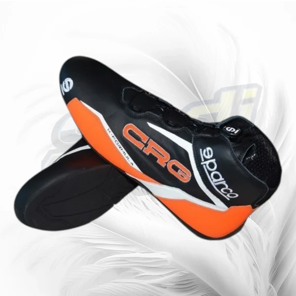 A pair of black and orange cycling shoes with white and orange branding, displayed against a white feather background.
